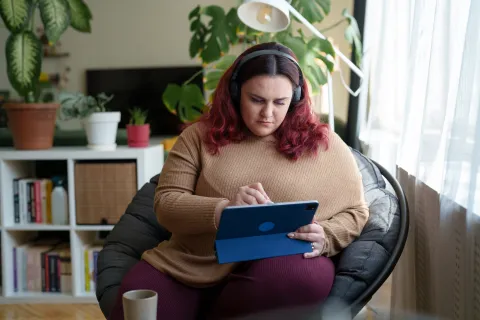 Woman with headphones using digital tablet and pen