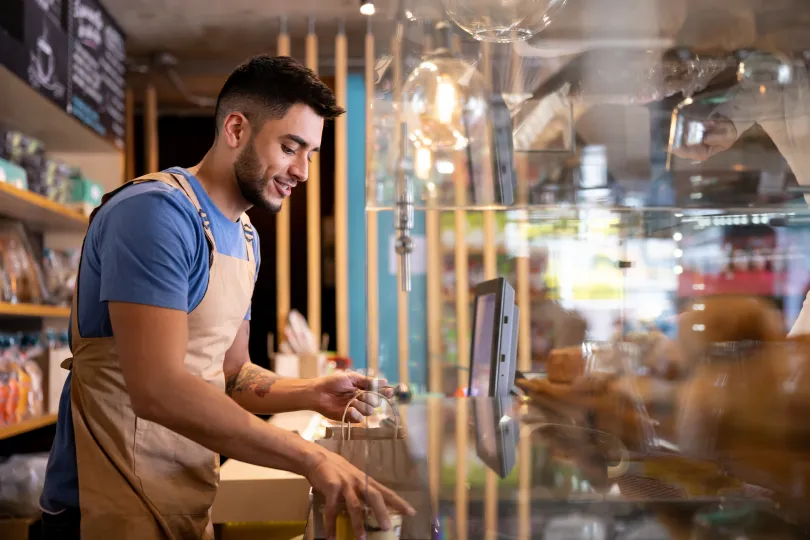 Waiter working at a cafe preparing a delivery order behind the counter 
