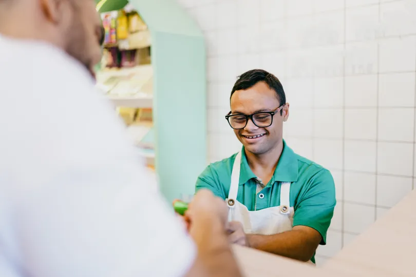 Young man with down syndrome working at the checkout counter