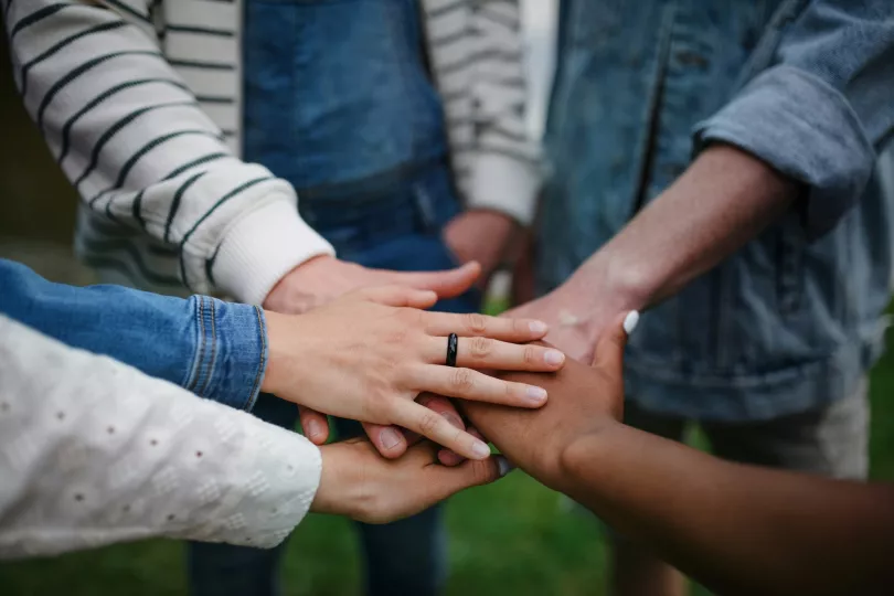 Several people touch hands in the middle of a circle
