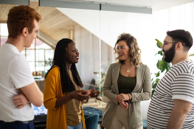 group of colleagues taking a break from work, standing at office, talking and smiling