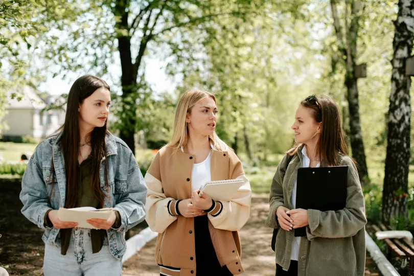 Three people converse outside in an educational setting