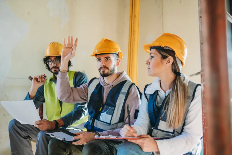Three apprentices are listening to their foreman on a construction site.