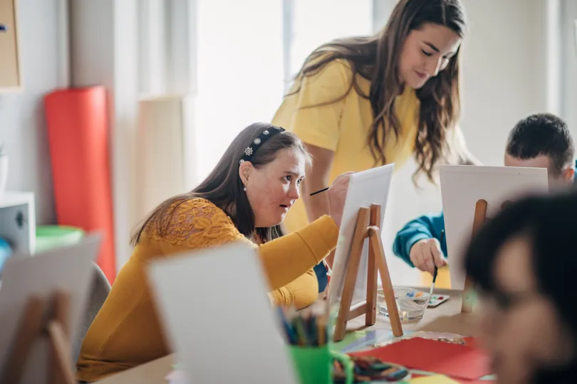 woman with down syndrome painting on canvas in an arts class