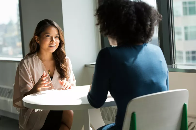 Two people converse over an empty table