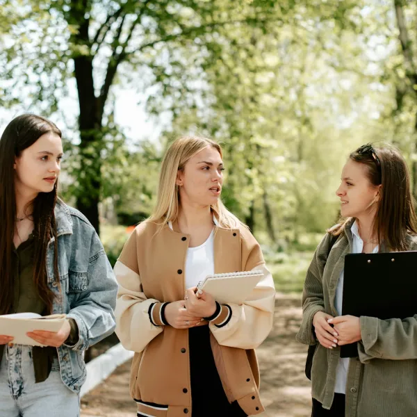 Three people converse outside in an educational setting