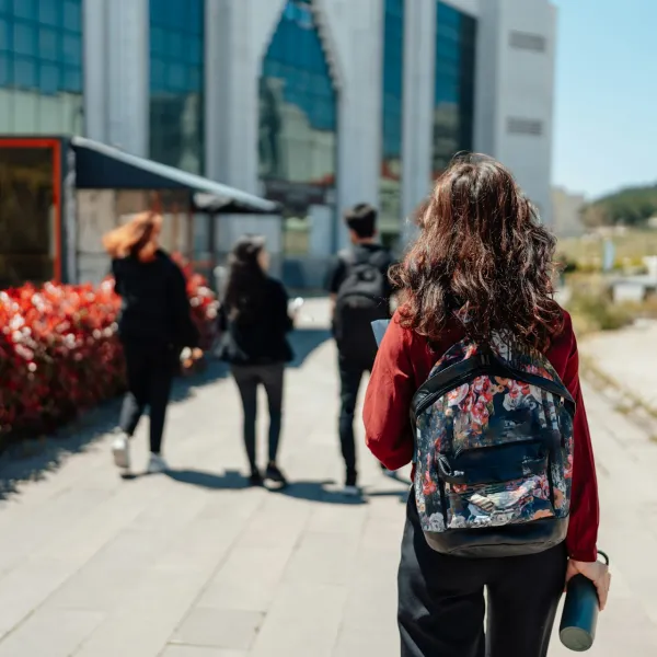 Several people walk away outside in an educational setting