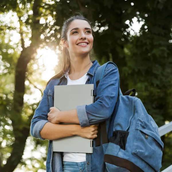 A person wearing a backpack smiles and looks away from the camera