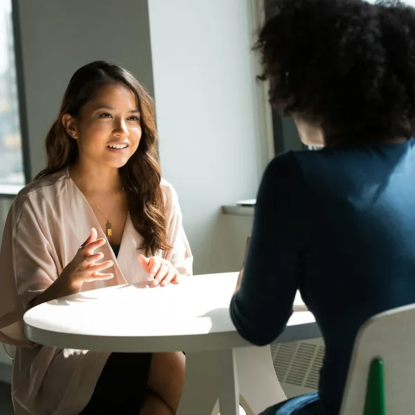 Two people converse over an empty table
