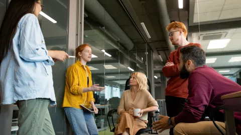 Five people converse in an industrial setting