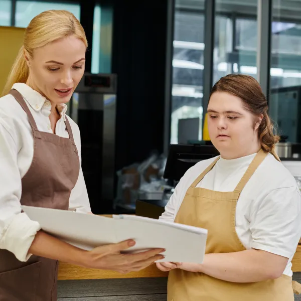 A young female employee engages with a colleague while preparing orders in a vibrant cafe