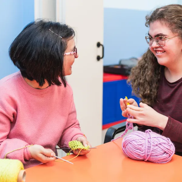Two mentally disabled students share a joyful moment in sewing class