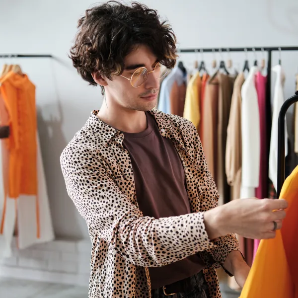 Young stylish man choosing new clothes on the rack