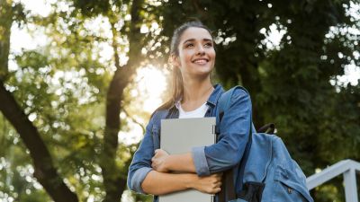 A person wearing a backpack smiles and looks away from the camera