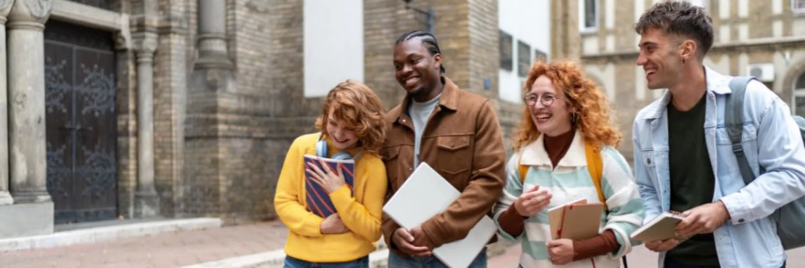 A group of diverse university students walking in college campus carrying books and talking